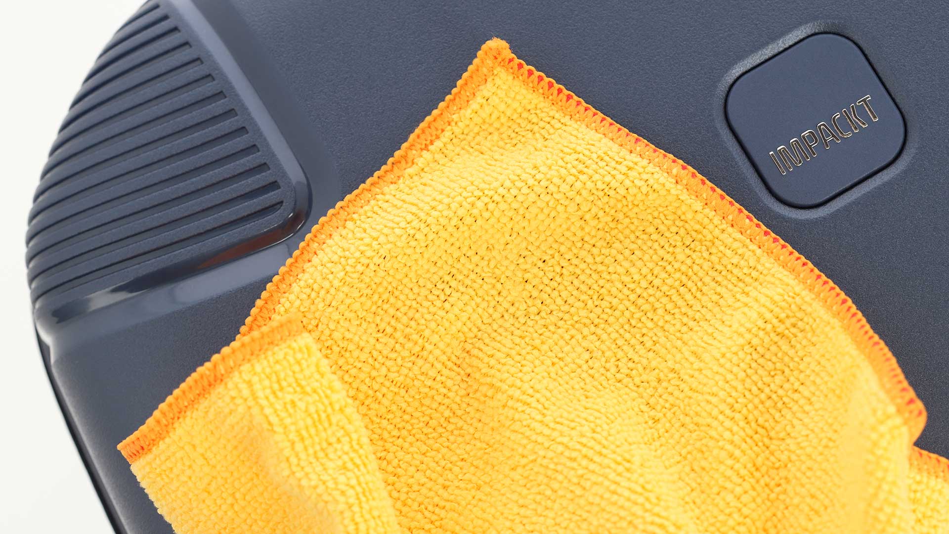 Detailaufnahme eines Computergehäuses mit gelbem Mikrofasertuch Nahaufnahme eines dunkelgrauen Computergehäuses mit einem gelben Mikrofasertuch auf der Oberfläche