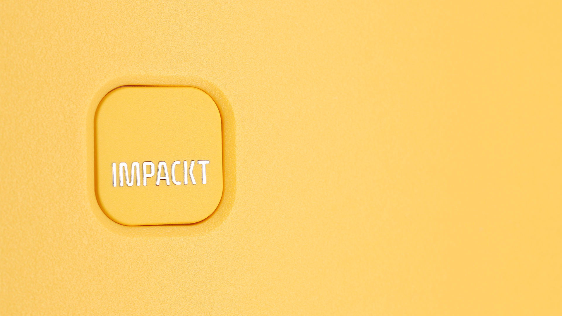 Nahaufnahme eines gelben Knopfes mit der Aufschrift 'IMPACKT' Gelber Knopf mit der Aufschrift 'IMPACKT' auf gelbem Hintergrund