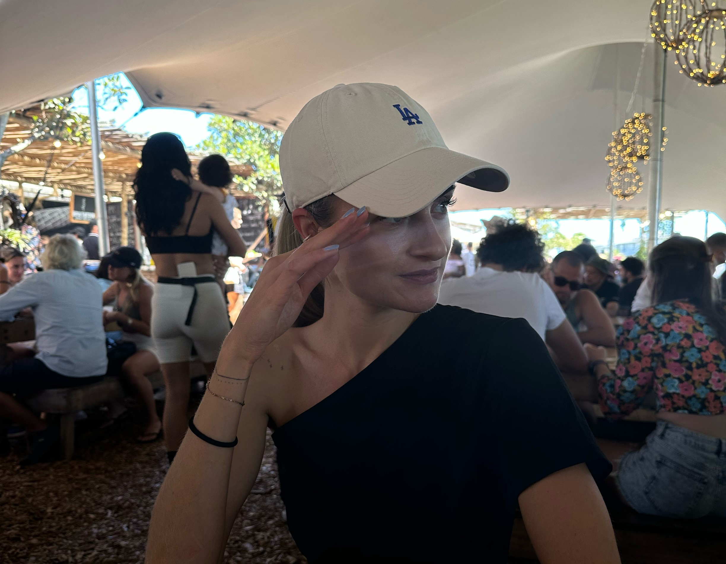 Zero Waste in Kapstadt: Hier kannst Du unverpackt einkaufen Eine junge Frau trägt eine weiße Baseballkappe und sitzt entspannt in einem gut besuchten Café mit vielen anderen Gästen.