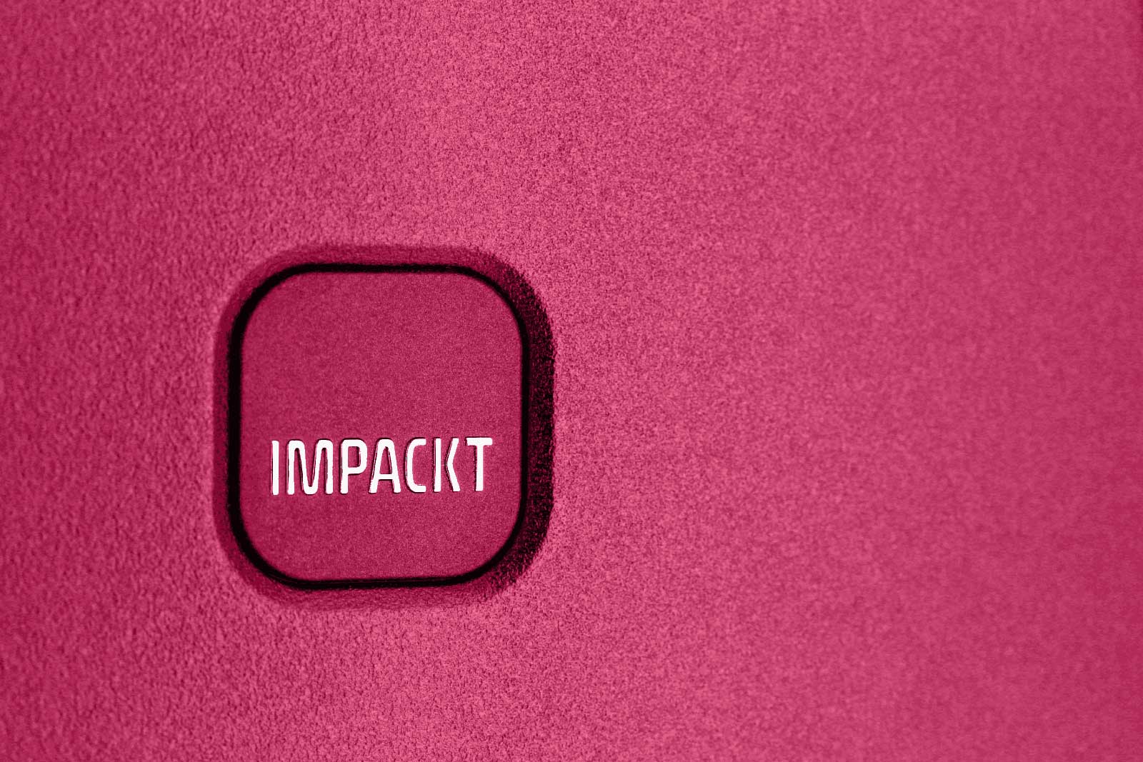 Nahaufnahme eines pinkfarbenen Hintergrunds mit quadratischem Logo mit der Aufschrift 'IMPACKT' Quadratisches Logo mit der Aufschrift 'IMPACKT' auf pinkfarbenem Hintergrund